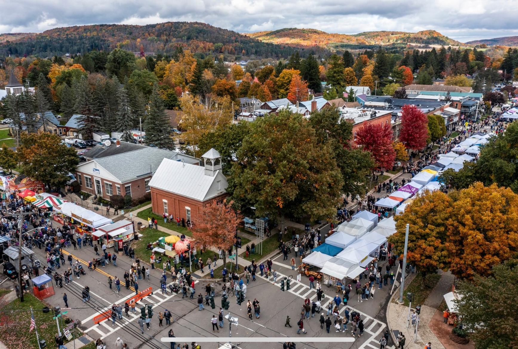Aerial view of a town square with people and tents during an outdoor event.